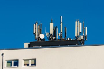 A rooftop equipped with numerous communication antennas showcases modern technology. Clear blue...