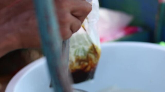 Close up A 'Dawet' ice seller is placing the dawet ice ordered by the buyer in plastic bag, Indonesian Iced Sweet Coconut Drink" or "Iced Dawet