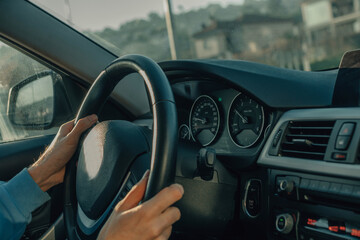 close-up young man's hands on the steering wheel driving