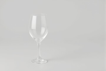A clear wine glass standing on a light gray background