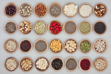 A colorful assortment of nuts, seeds, and snacks displayed in ceramic bowls on a wooden surface