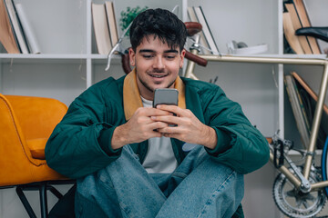 young man at home sitting on the floor looking at his mobile phone
