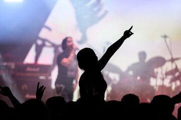 Cheering crowd silhouetted against bright stage lights