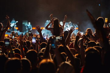 Crowd cheering and filming with smartphones at live music concert