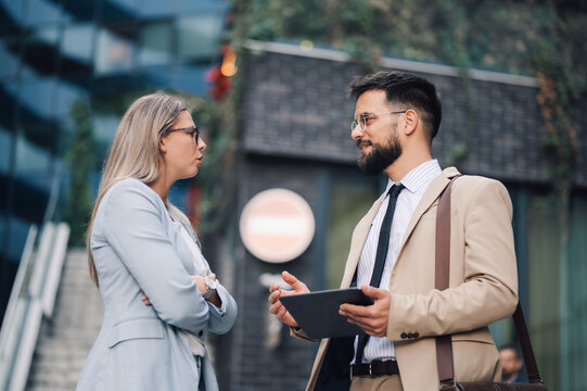 Businessman holding tablet explaining something to businesswoman looking unconvinced