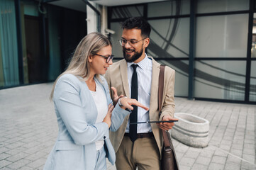 Business people using digital tablet having conversation outside office building