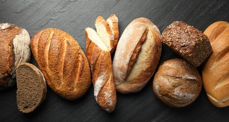 Loafs of different bread on black background, flat lay