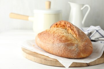 Loaf of delicious bread on white wooden table. Space for text