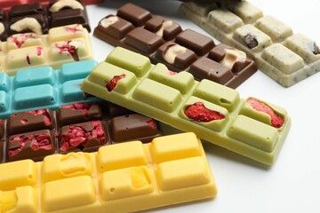 Different tasty chocolate bars on white background, closeup