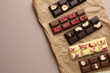 Different tasty chocolate bars on beige background, top view. Space for text