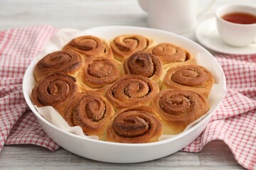 Freshly baked cinnamon rolls on light wooden table, closeup