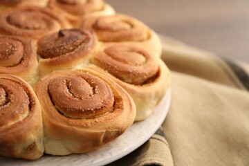 Freshly baked cinnamon rolls and napkin on blurred background, closeup