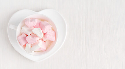 Top view of heap of sweet festive marshmallow heart shaped dessert snack baked from sugar and gelatin served on plate on white wooden background with copy space used for celebration of valentines day
