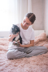 Obraz premium A young woman sits on a plush, pink bed, cradling a black and white rabbit. The scene is calm and intimate, highlighting the bond between human and pet.