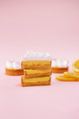 Lemon tart covered with white meringue cut in half isolated on the pink background
