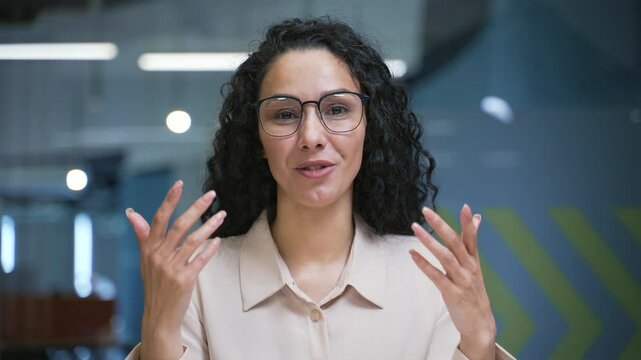 Webcam view. Smiling businesswoman talking on a video call looking at camera sitting in office. Female manager has a business meeting. Coach speaks remotely at an online course or training. Close up