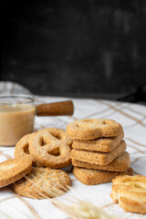 Danish shortbread cookies on a white towel, boiled condensed milk in a glass milk jug, light still life, wheat ears, tea with cookies