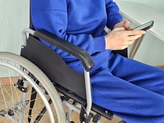 Person using smartphone while seated in wheelchair indoors