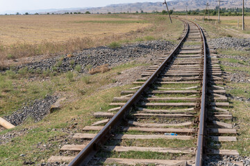 A train track with a grassy area in the background. The train tracks are old and rusty