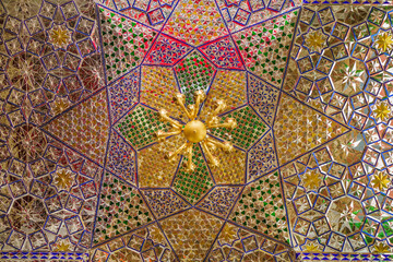Mirrored ceiling of intricate geometric patterns in the shrine of a Shiite saint or imam. There is a chandelier in the center. Shot in the shrine of Imamzadeh Mohammed Helal, Aran va Bidgol, Iran