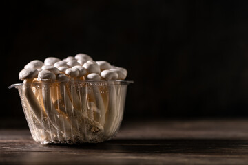 Closeup of a bunch of shimeji mushrooms on wooden board, with selective focus