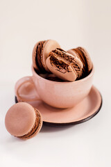 Bitten chocolate french macaron in a beige cup isolated on white background