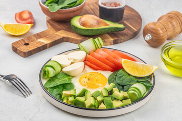 Healthy vegetarian salad breakfast Spinach leaves, tomato, avocado, cheese and egg on a light background. Top view. Buddha bowl