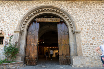 A large wooden door with a sign that says "Caracas" on it. The door is open and there are people walking through it