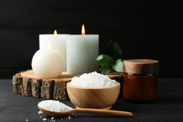 Composition with cosmetic products and candles for spa treatment on black wooden table