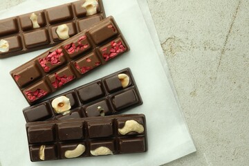 Delicious chocolate bars with different flavors on light table, flat lay. Space for text