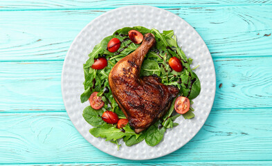 Grilled chicken legs with tomatoes and salad . Top view