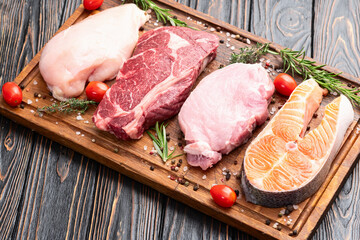 Mix of raw meat and fish . Salmon , beef , pork , chicken staek . Top view