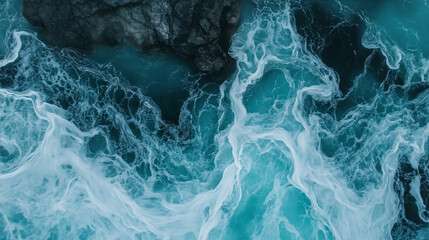 Obraz premium Turbulent blue ocean waves crashing against rocks in a dramatic aerial view