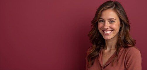 Smiling woman with wavy hair against burgundy background