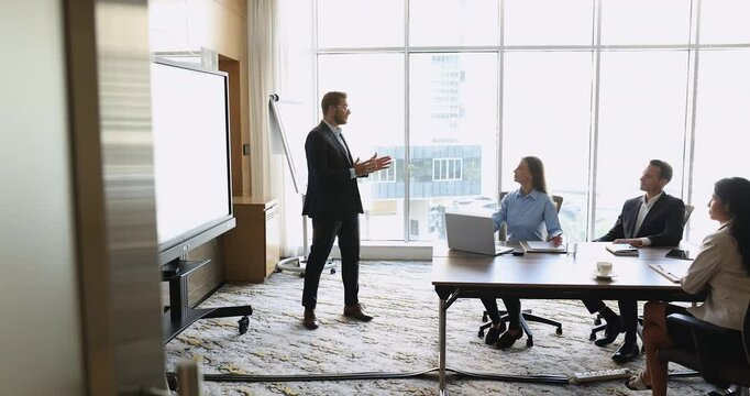 Young Arabian business trainer dressed in suit standing in front of audience, gives presentation to team, gather in conference room, discussing strategy or project updates. Seminar event, leadership