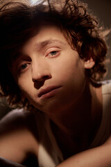 Vertical portrait of handsome young adult man with blue eyes and sharp cheekbones illumed with golden sunray