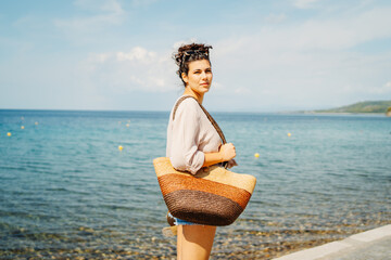 Young caucasian woman is going to the beach with straw bag	
