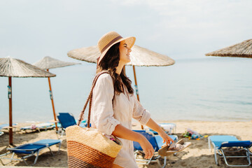 Young caucasian woman is going to the beach with straw bag	
