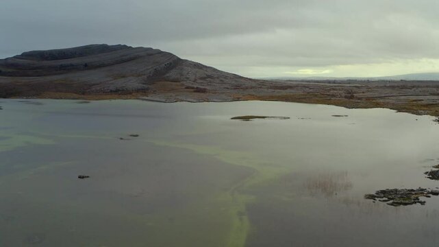 Tracking Aerial Shot of Mullaghmore Mountain with Seasonal Lake in Foreground. Burren