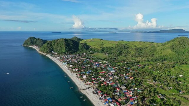 A panoramic aerial view of the lush mountains of Mabua and Looc, pebble beaches, deep blue waters, and the stunning islands of Hikdop and Danawan on the horizon in the Philippines.
