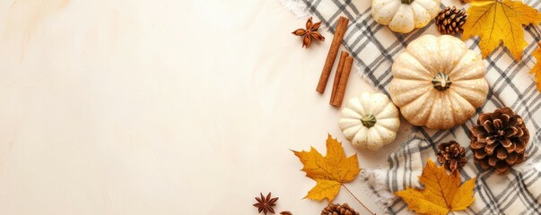 Fototapeta premium Capture charm of autumn with inviting setup: top view featuring soft plaid, small pumpkins, yellow maple leaves, pine cone, cinnamon sticks, anise on pastel beige backdrop. Perfect for messages or ads