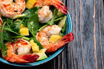 Salad with tiger shrimps , avocado and mango . Top view