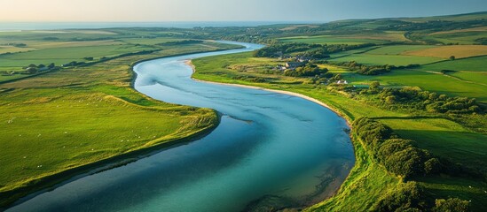 Fototapeta premium Aerial view River meandering through green fields, village backdrop