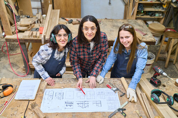 Team of women collaborating on woodworking project in lumberyard