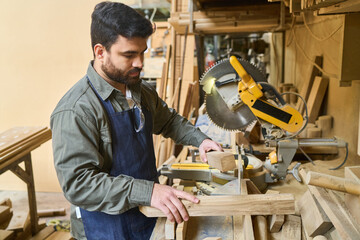 Young carpenter working with wood in a busy lumberyard workshop