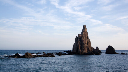 Rugged rock formations in calm sea under blue sky