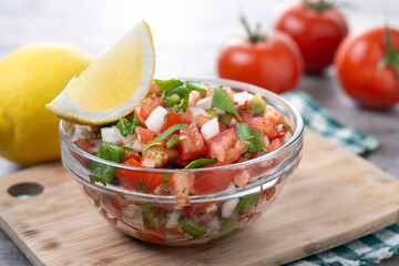Traditional Mexican Pico de Gallo sauce in bowl on wooden table