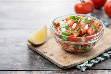 Traditional Mexican Pico de Gallo sauce in bowl on wooden table. Copy space
