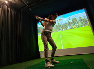 Indoor golf practice session with a simulator in a modern setting