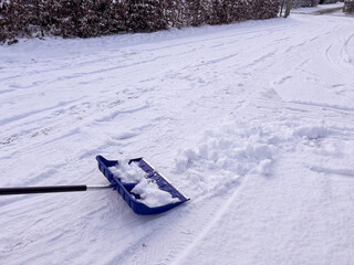 A blue snow shovel on the street covered with snow in winter 